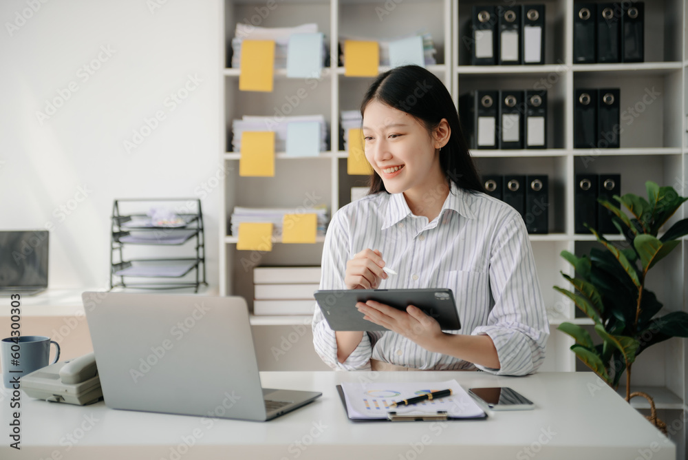 Young beautiful woman typing on tablet and laptop while sitting at the working wooden table office. Young beautiful woman typing on tablet and laptop while sitting at the working wooden table office.