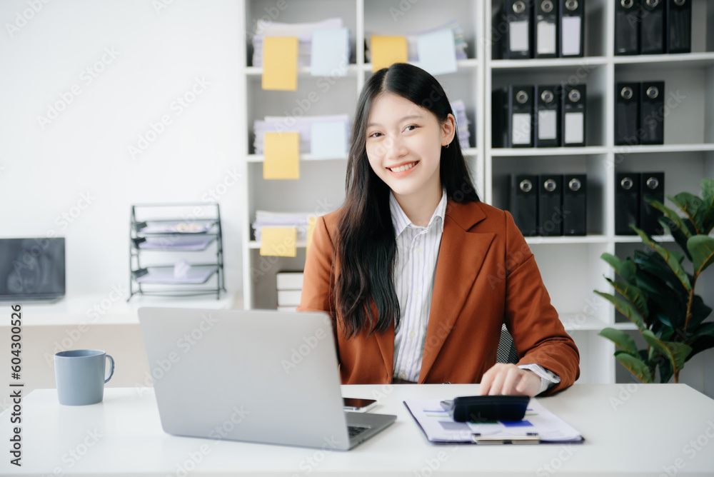 Young beautiful woman typing on tablet and laptop while sitting at the working wooden table office. Young beautiful woman typing on tablet and laptop while sitting at the working wooden table office.