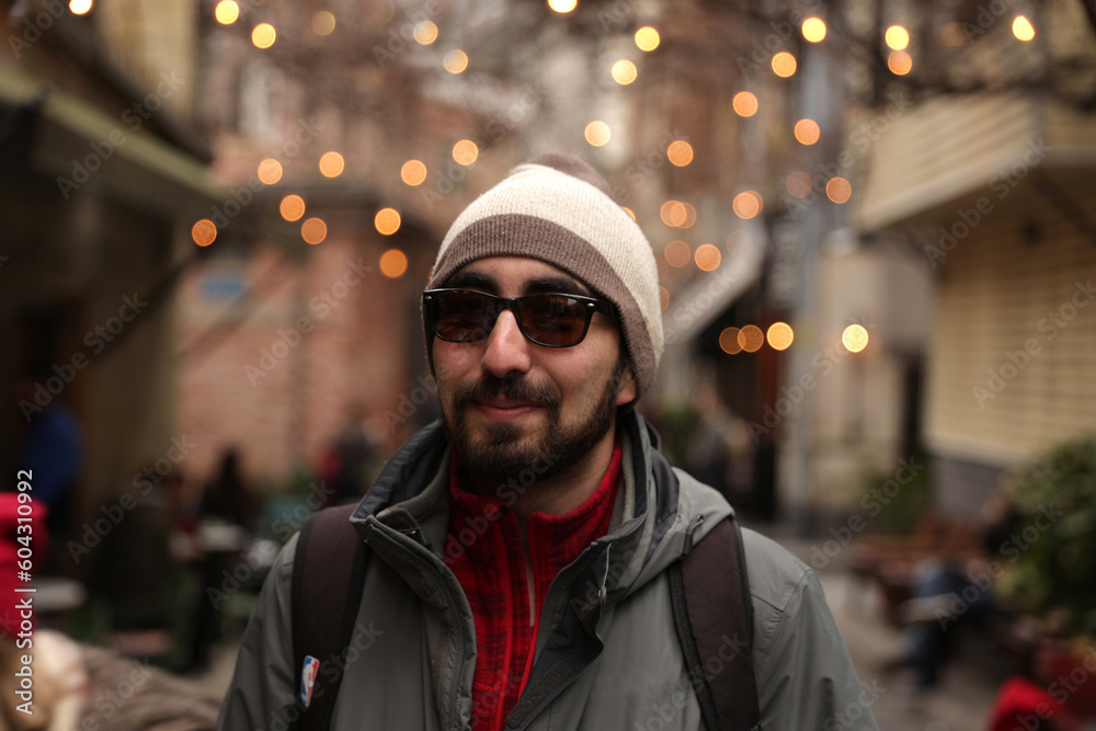 Bearded hipster man with a beret and sunglasses in front of a blurry background with light bulbs Bearded hipster man with a beret and sunglasses in front of a blurry background with light bulbs