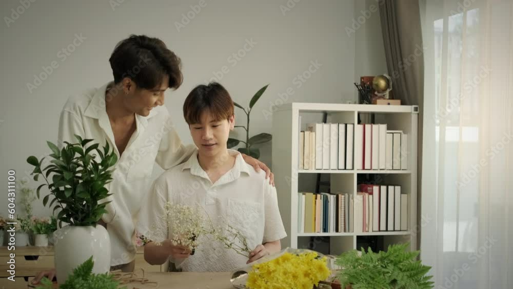 Shot in slow motion. Happy moment of young asian gay couple talking to etch other, arranging flowers at home. Love, romance and relationships