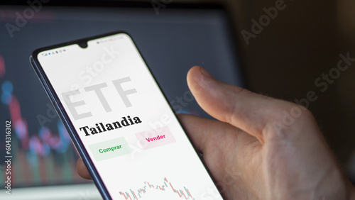 An investor analyzing an etf fund. ETF text in Spanish : Thailand, buy, sell.