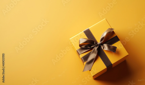 Gift box with golden satin ribbon and bow on yellow background. Holiday gift with copy space. Birthday or Christmas present, flat lay, top view. Christmas gift box concept. Generative AI
