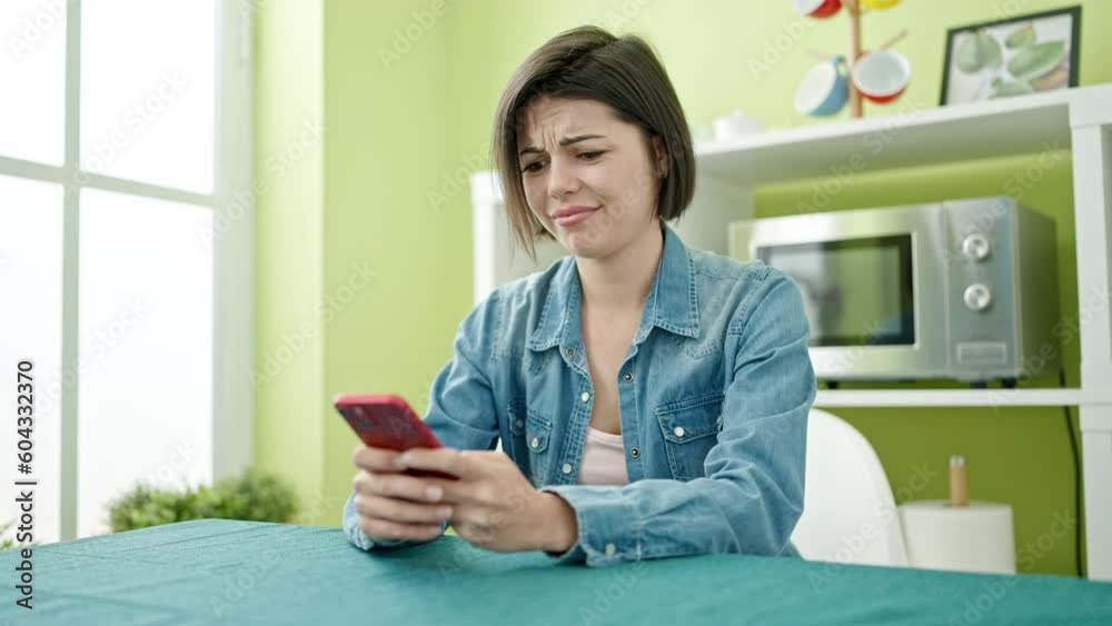 Young caucasian woman using smartphone sitting on table at home Young caucasian woman using smartphone sitting on table at home