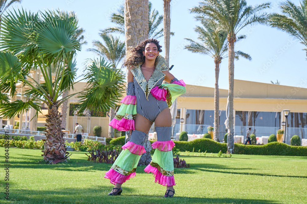 Brazilian Samba Dancer wearing colorful carnival costume.Gorgeous brazilian woman dancing and smiling on summer palms background.