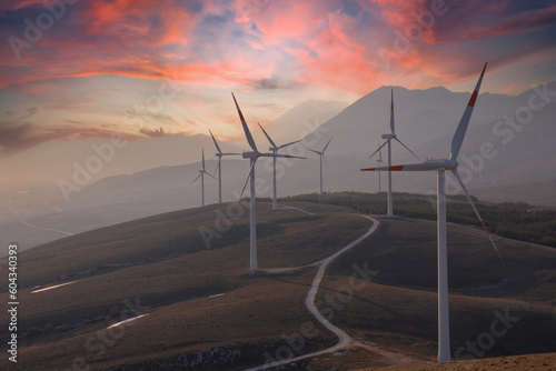 A wind farm or wind park at sunset clouds located in the mountains of Italy Europe and it allows to realize clean energy. It’s sustainable, renewable energy for enviromental