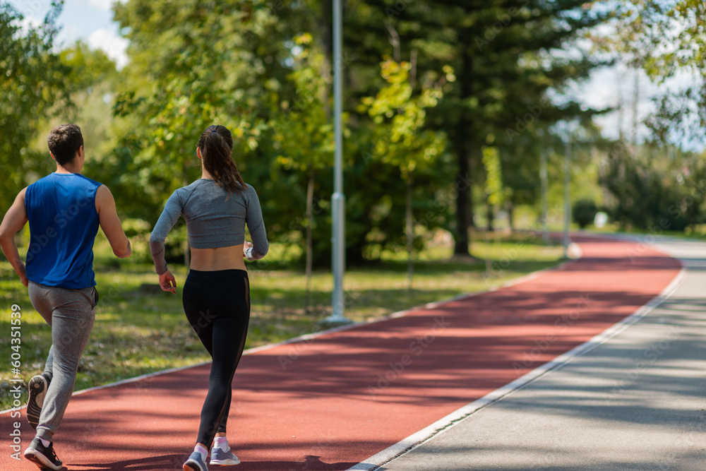 Fit couple running on a sports track in the park Fit couple running on a sports track in the park