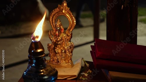 Hindu God golden statue with lamp. Lord statue with an oil lamp on a local business counter.