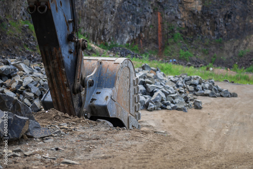 Excavator bucket at basalt quarry. Basalt mining. Excavators in a basalt quarry near the forest.