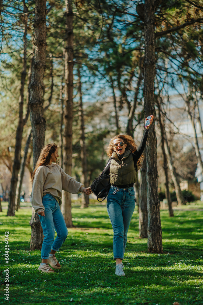 Blonde curly haired girl laughing while hanging out with her female friend. They are holding their hands. Front view shot