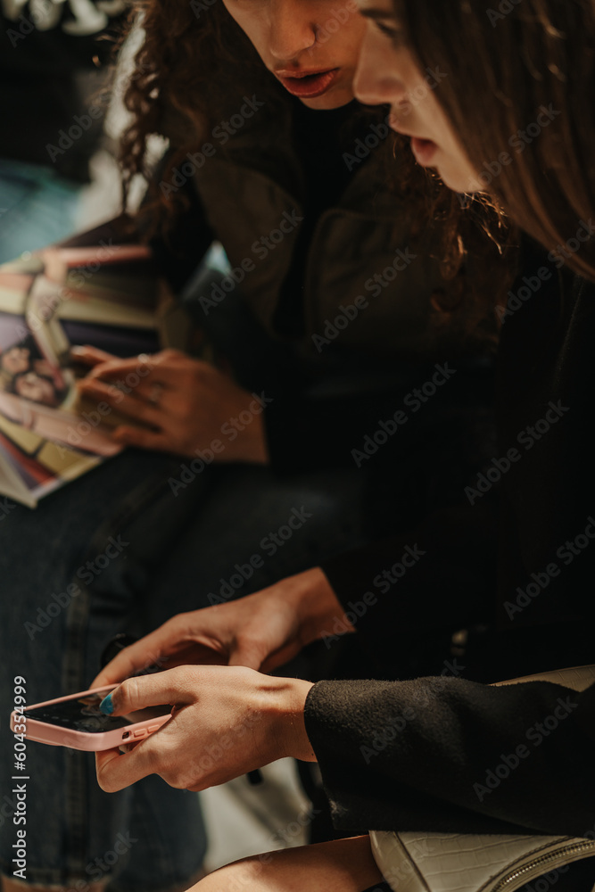 Obraz premium Girl showing something on the phone to her friend. Close up shot