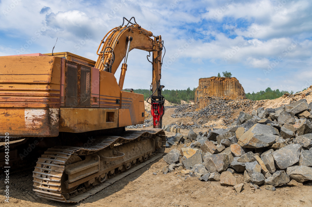 Basalt mining. Yellow excavators in a basalt quarry near the forest. Basalt mining. Yellow excavators in a basalt quarry near the forest.