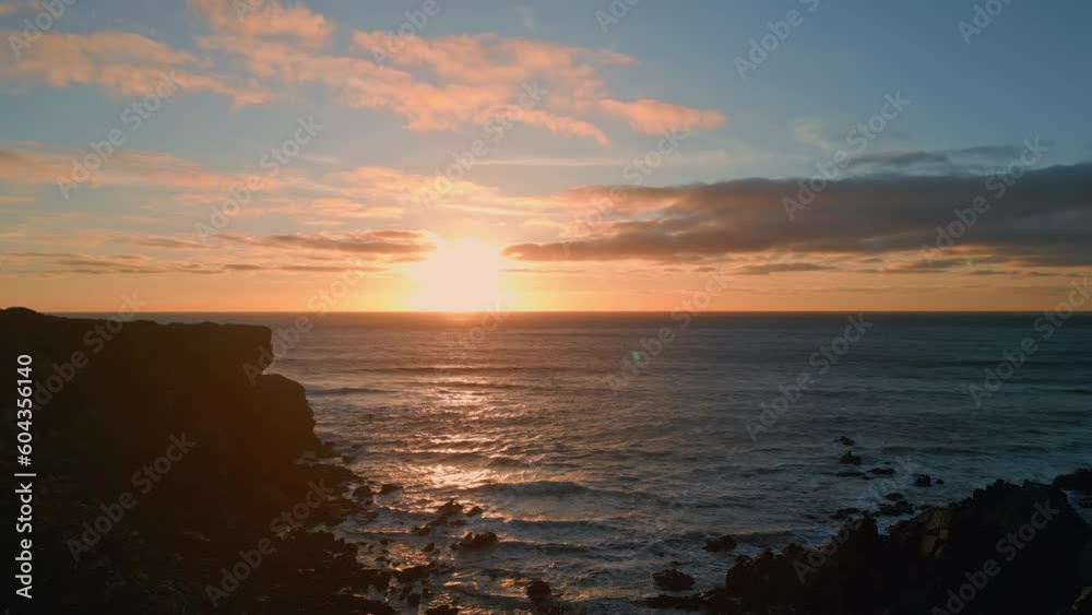 Sunset mountain hill silhouette sea coastline. Drone view dark cliffs calm ocean Sunset mountain hill silhouette sea coastline. Drone view dark cliffs calm ocean