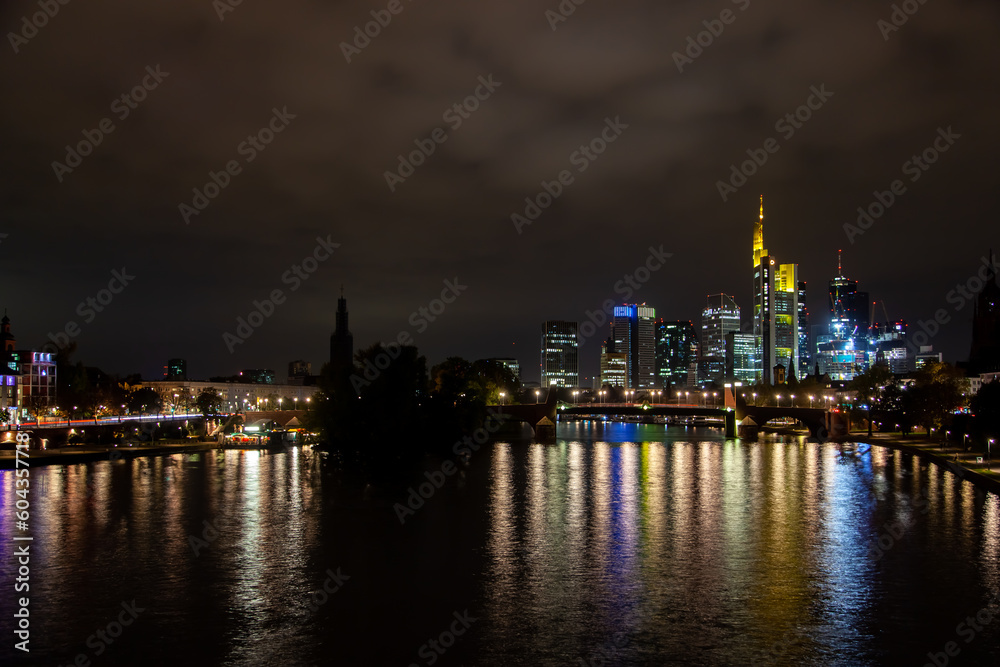  of Frankfurt's illuminated skyline, bridge traffic, and city lights reflecting on the river during a partly cloudy autumn night.