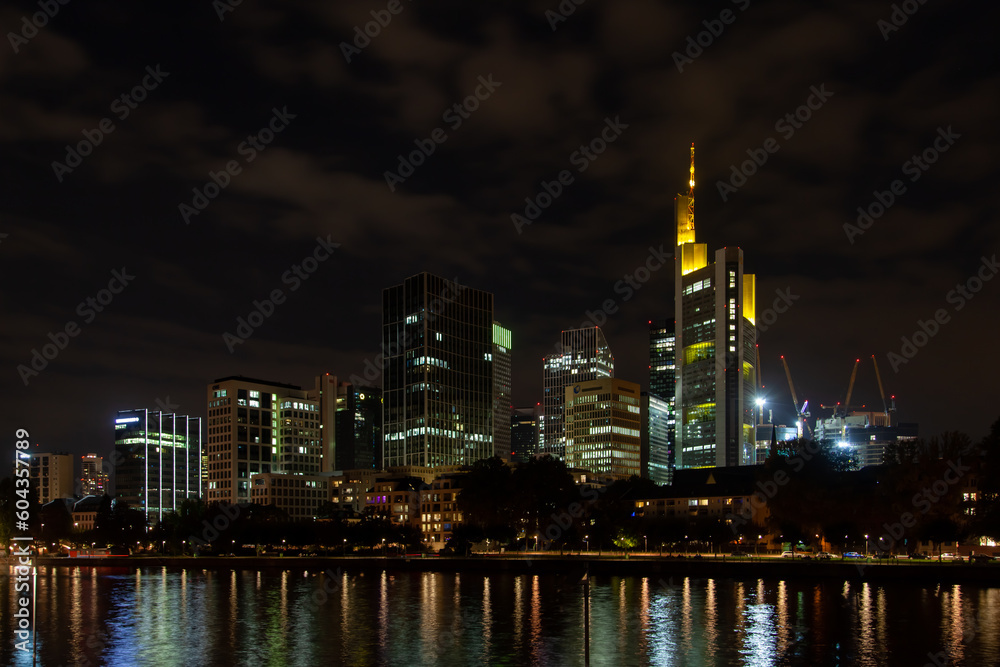 Nighttime  of Frankfurt cityscape highlighting the river, lit skyscrapers, and their reflection. Perfect for urban backgrounds and ads.