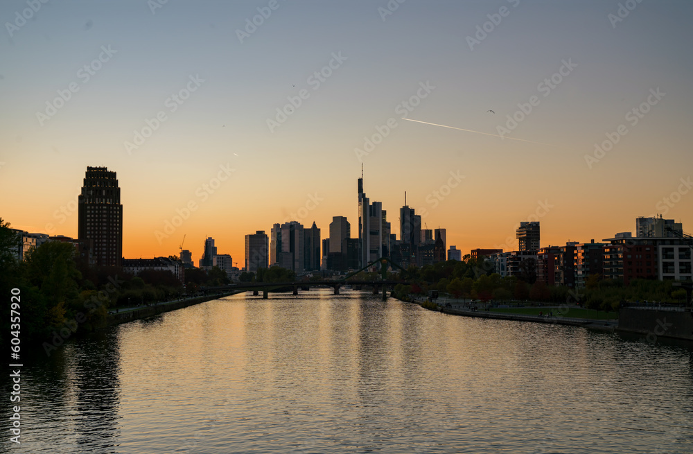 Stunning  of a beautiful sunset in Frankfurt, Germany, showcasing the city skyline, a bridge over the river, and skyscrapers with reflections.