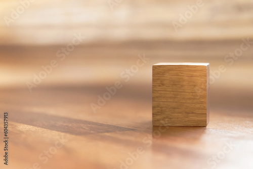 Blank wooden cube block on wooden table with shades of light through the window. Copy space for your text or number.