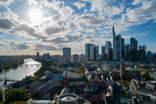 Stunning of Frankfurt's cityscape with its iconic skyline, skyscrapers, bridge, and river during the day under a partly cloudy autumn sky.