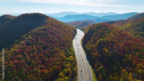 Aerial view of I-40 freeway in North Carolina heading to Asheville through Appalachian mountains in golden fall with moving trucks and cars. Interstate transportation concept