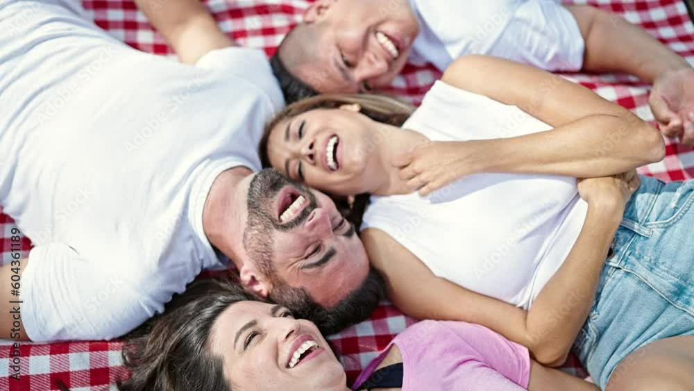 Group of people laying on picnic blanket smiling at park Group of people laying on picnic blanket smiling at park