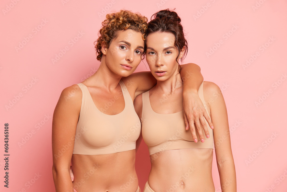 Two female models advertising ergonomic sport bras stand embracing