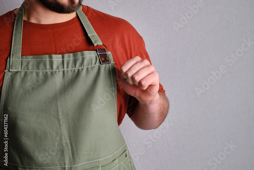 A man in a kitchen apron. Chef work in the cuisine. Cook in uniform, protection apparel. Job in food service. Professional culinary. Green fabric apron, casual stylish clothing. Handsome baker posing © Iuliia Pilipeichenko