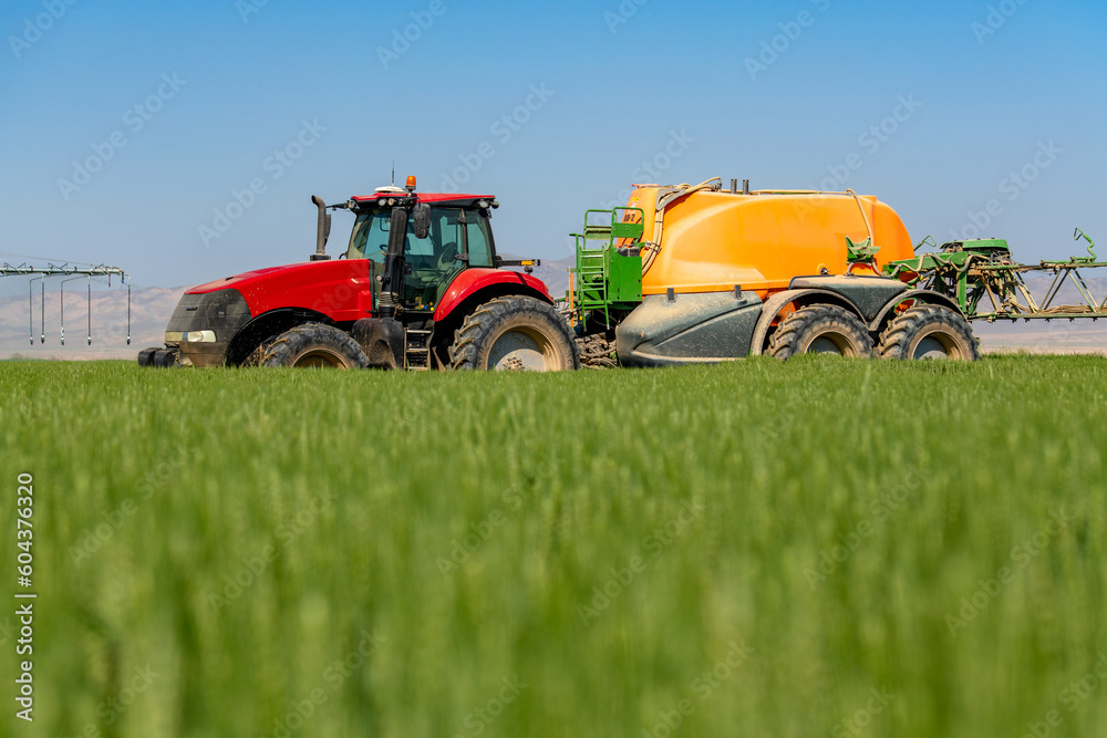 Tractor spray fertilizer on green field. Farming tractor plowing and spraying on field. Tractor spray fertilizer on green field. Farming tractor plowing and spraying on field.
