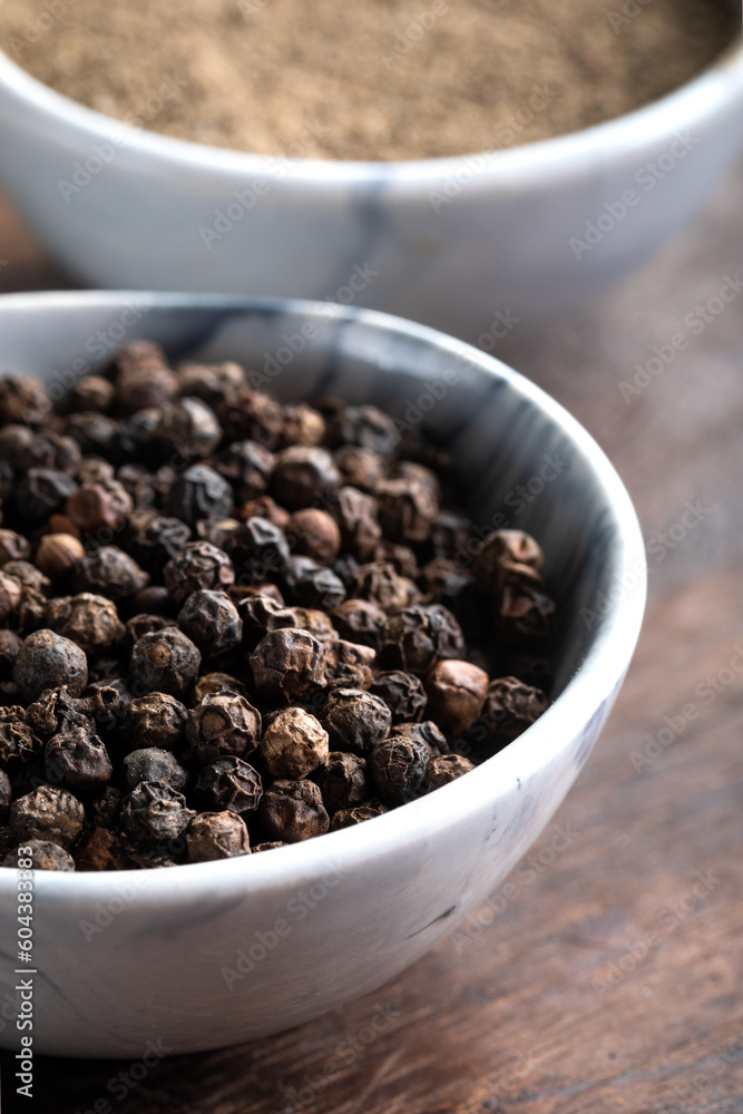 Black peppercorns (Black pepper) in a bowl on a wooden background. Black peppercorns (Black pepper) in a bowl on a wooden background.
