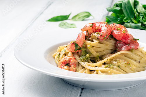 Piatto di deliziose linguine condite con pesto alla genovese e gamberi, cibo italiano  photo