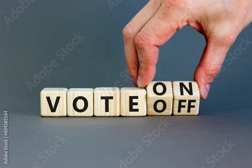 Vote on or off symbol. Businessman turns wooden cubes and changes word Vote off to Vote on. Beautiful grey table grey background. Business and vote on or off concept. Copy space.