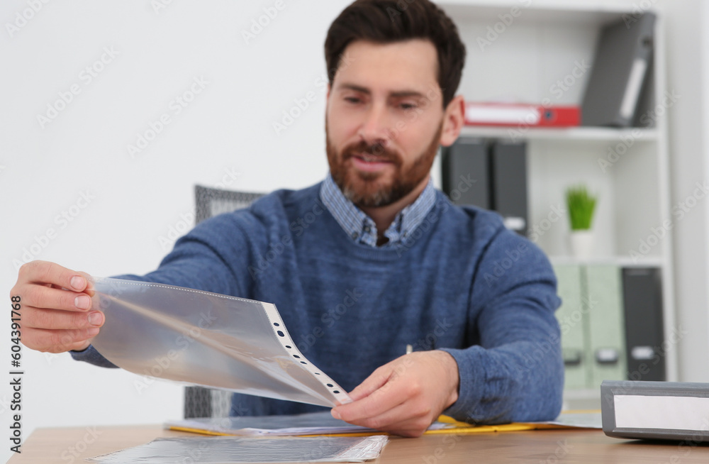 Businessman taking punched pocket on wooden table in office, selective focus Businessman taking punched pocket on wooden table in office, selective focus