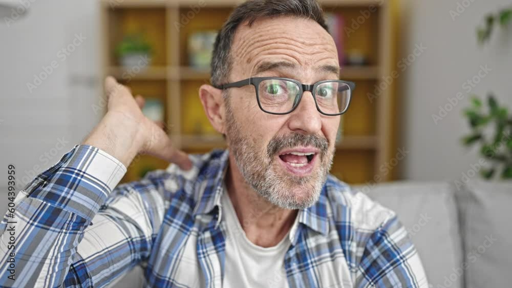Middle age man doing silent gesture closing mouth at home Middle age man doing silent gesture closing mouth at home
