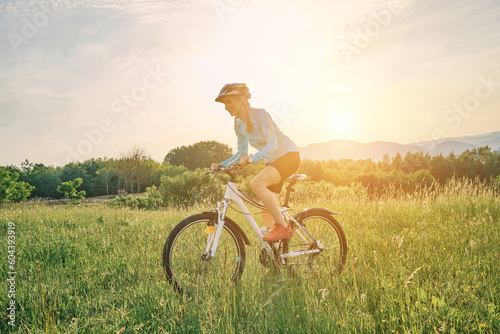 Cyclist Woman riding bike in helmets go in sports outdoors on sunny day a mountain in the forest. Silhouette female at sunset. Health care, authenticity, sense of balance and calmness. 