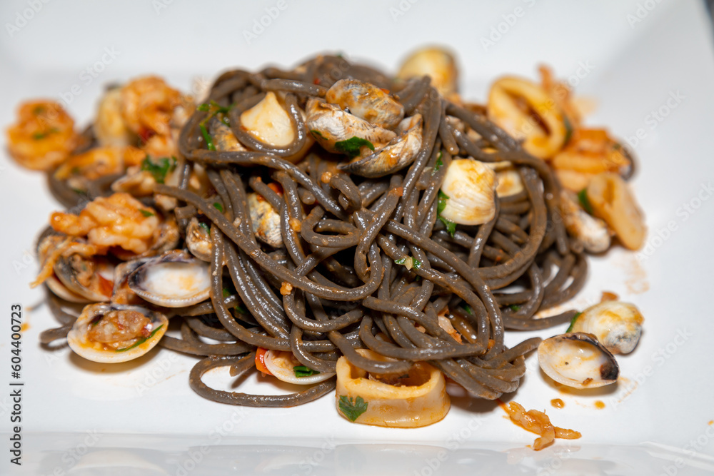 Fototapeta premium Black spaghetti with sepia squid ink with seafood, clams and shells. Nero di seppia