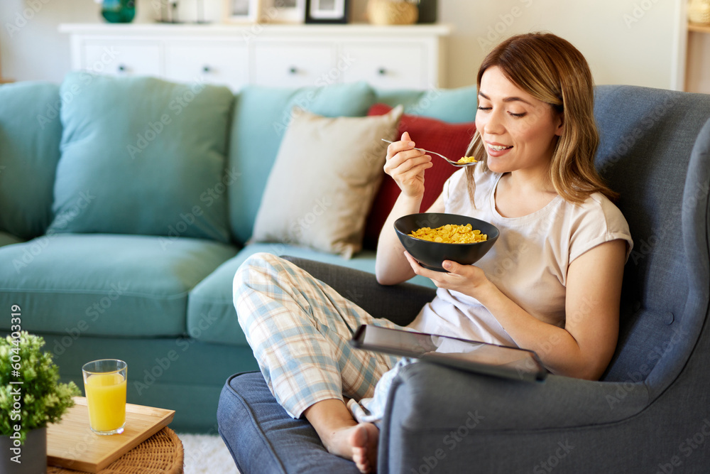 Smiling woman with digital tablet and breakfast at home Smiling woman with digital tablet and breakfast at home