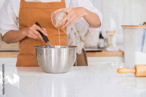 Woman pouring ingredient into mixing bowl.