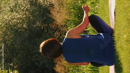 Fitness woman practicing asana yoga pose near lake at sunrise. Vertical video photo