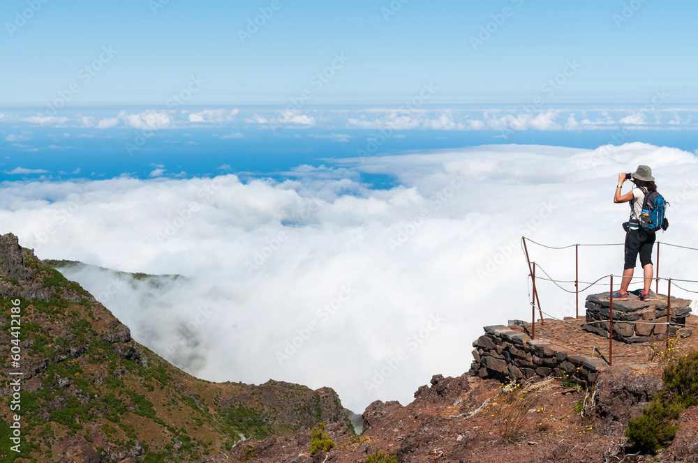 Una senderista hace una fotografía en la levada de pico Ruibo sobre un mar de nubes en la isla de Madeira, Portugal.