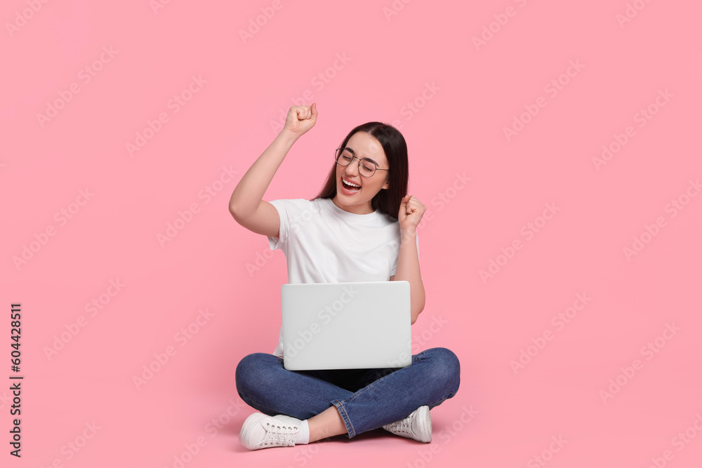 Naklejka premium Happy young woman with laptop on pink background