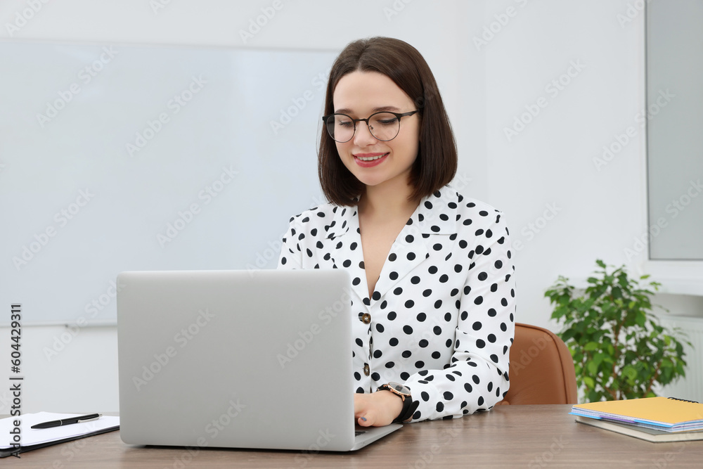 Happy young intern working with laptop at table in modern office Happy young intern working with laptop at table in modern office