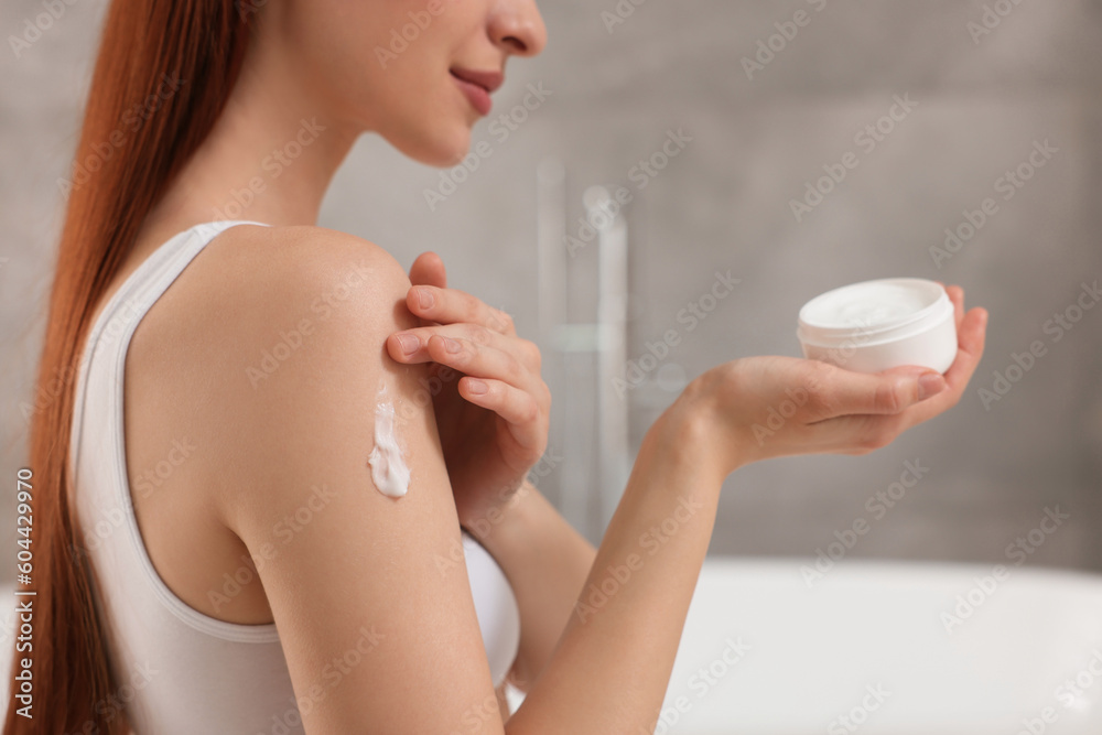 Young woman applying body cream onto shoulder in bathroom, closeup Young woman applying body cream onto shoulder in bathroom, closeup