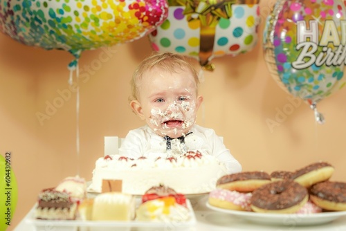 A small child with a smeared face in a cake is crying.