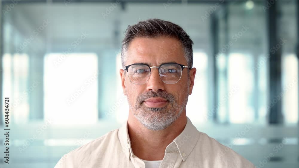Headshot close up portrait of indian or latin confident mature good looking middle age leader, ceo male businessman on blur office background. Handsome hispanic senior business man looking at camera.