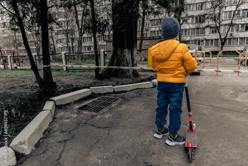 A boy with a scooter against the backdrop of a gloomy city