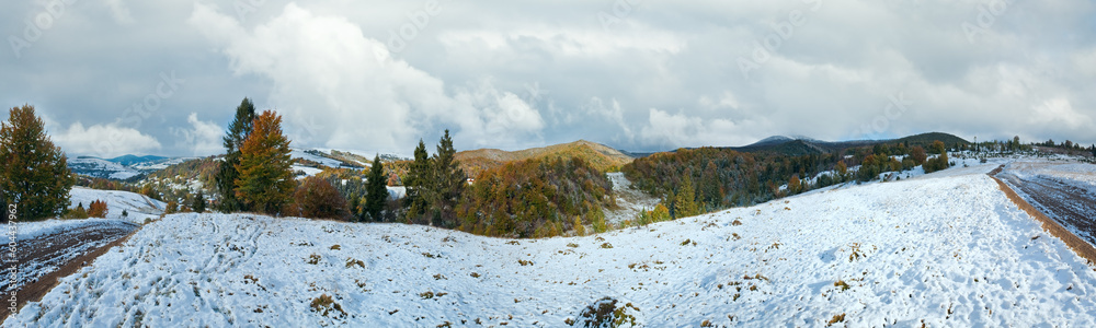 October Carpathian mountain panorama with first winter snow on dirty road.