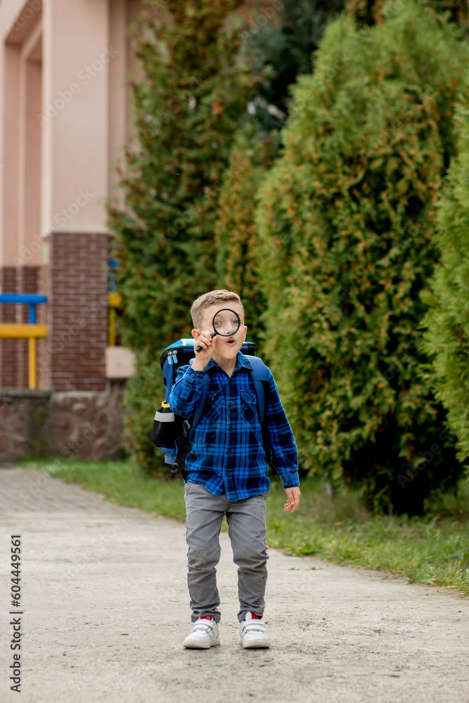 Schoolboy looking through a magnifying glass, with a surprised expression, squinting his eyes Schoolboy looking through a magnifying glass, with a surprised expression, squinting his eyes