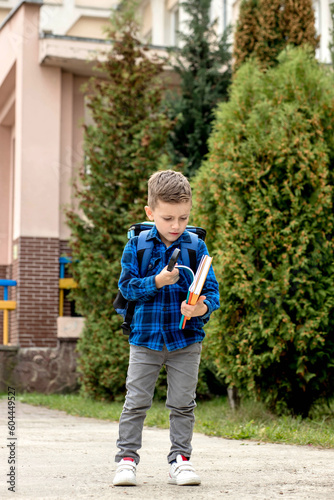Little first grader with backpack looking the copybook, going home from school