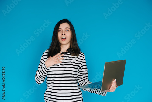 Excited Woman in Striped Sweater Writing Email on Laptop - Modern Technology and Communication Concept - Empty Space for Text - Isolated on Blue Background - Perfect for Business and Technology Themes