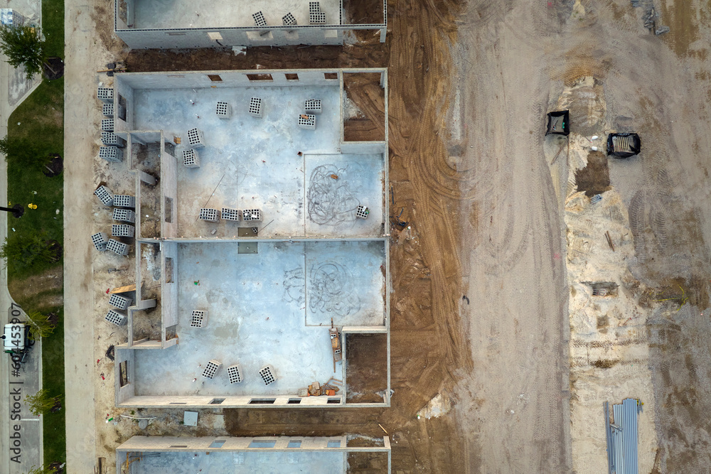Aerial view of unfinished frame of private house with brick concrete walls ready for mounting wooden roof beams under construction Aerial view of unfinished frame of private house with brick concrete walls ready for mounting wooden roof beams under construction