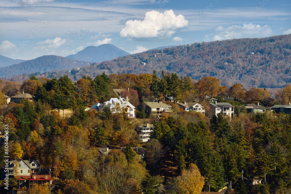 View from above of expensive residential houses high on hill top between yellow fall trees in suburban area in North Carolina. American dream homes as example of real estate development in US suburbs