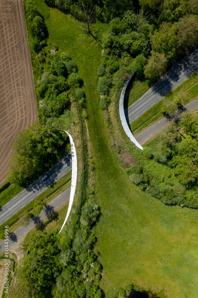 Vertical aerial frame of road traversed by wildlife crossing forming a safe natural corridor bridge for animals to wander between natural parks. Environment nature reserve infrastructure eco passage.